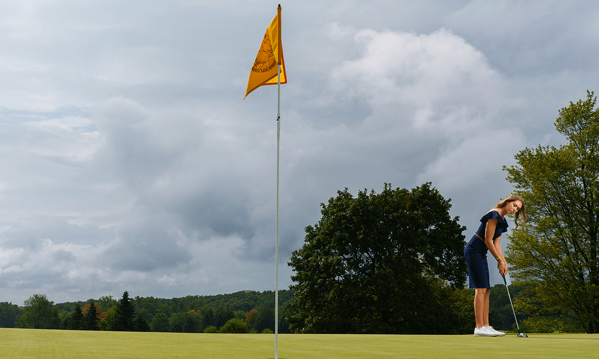 woman putting a golf ball into the hole